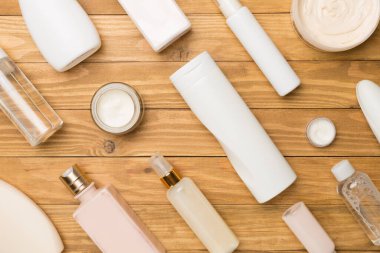 Ahşap arka planda farklı kozmetik şişeler ve konteynırlar..
