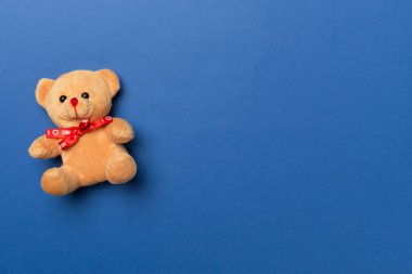 Cute teddy bear on color background, top view