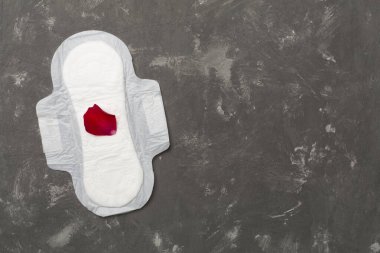 Beton arka planda kırmızı yapraklı regl yastığı, üst görünüm