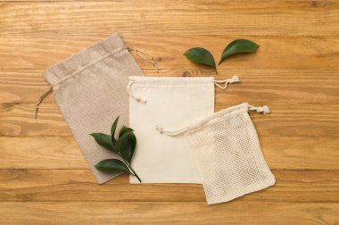 Small eco sacks with green leaves wooden on background. Top view