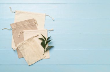 Small eco sacks with green leaves wooden on background. Top view