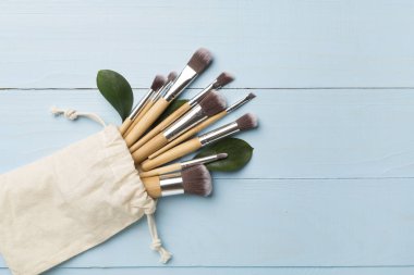 Natural biodegradable makeup brushes on wooden background, top view