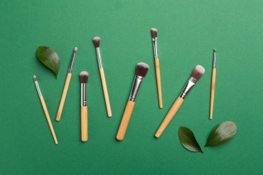 Natural biodegradable makeup brushes on color background, top view
