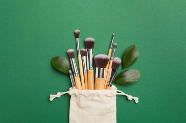 Natural biodegradable makeup brushes on color background, top view
