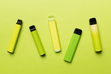 Disposable electronic cigarettes on color background, top view