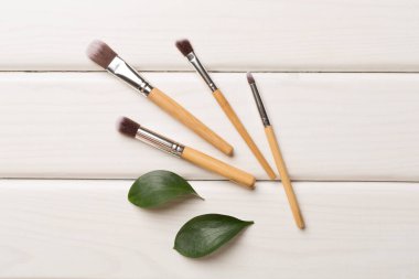 Natural biodegradable makeup brushes on wooden background, top view