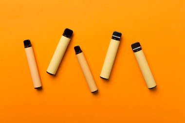 Disposable electronic cigarettes on color background, top view