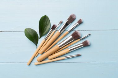 Natural biodegradable makeup brushes on wooden background, top view