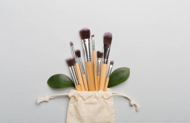 Natural biodegradable makeup brushes on color background, top view