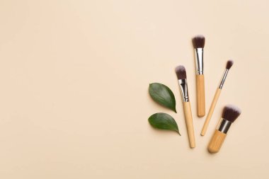 Natural biodegradable makeup brushes on color background, top view