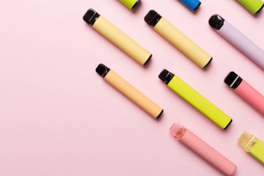 Disposable electronic cigarettes on color background, top view