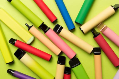 Disposable electronic cigarettes on color background, top view