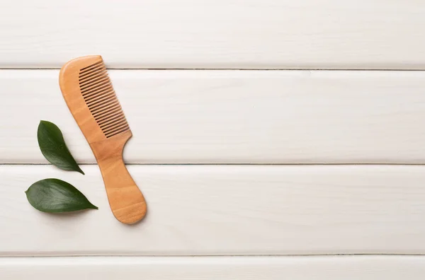 stock image Hair comb with green leaves wooden on background. Top view