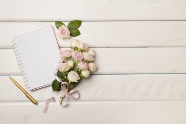 Ahşap arka planda defter ve gül çiçekleri, üst manzara.