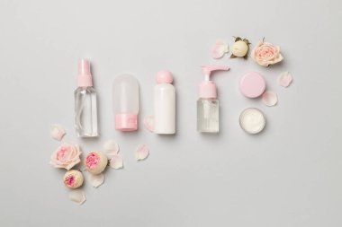 Set of small cosmetic bottles on color background, top view.