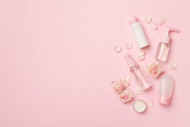 Set of small cosmetic bottles on color background, top view.