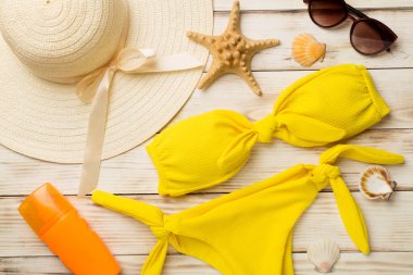 Güzel sarı bikini ve aksesuarlar renkli ahşap arka plan, üst manzara.
