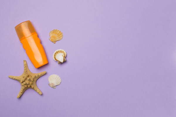 Бутылка с солнцезащитным кремом и раковинами на цветном фоне, вид сверху.