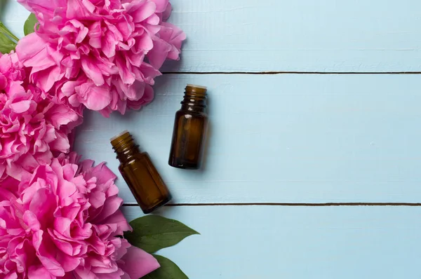 stock image Peony flower essentials oils on wooden background, top view.