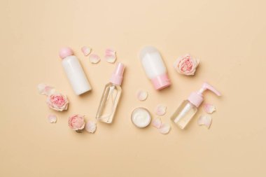 Set of small cosmetic bottles on color background, top view.
