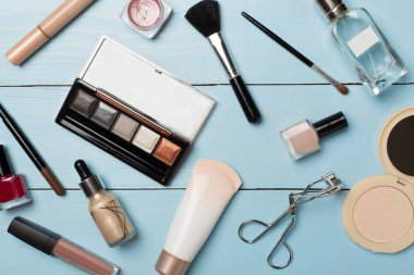 Ahşap arka planda farklı makyaj ürünleri, üst görünüm.