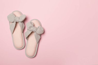 Soft pink slippers on color background, top view.