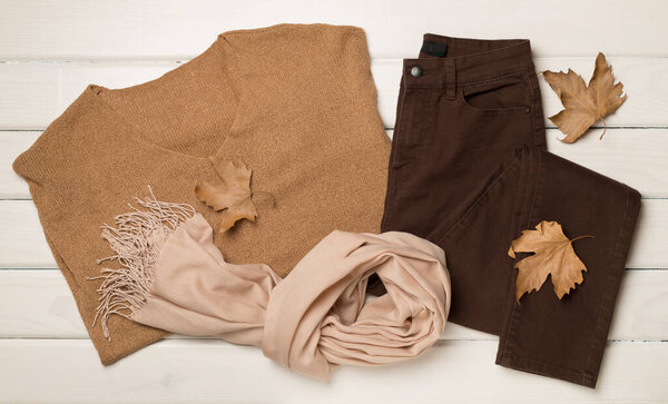Flat lay of women's stylish autumn outfit on wooden background.