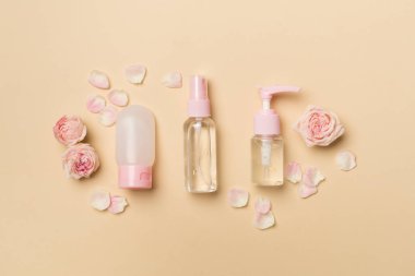 Set of small cosmetic bottles on color background, top view.