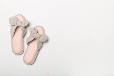 Soft pink slippers on color background, top view.