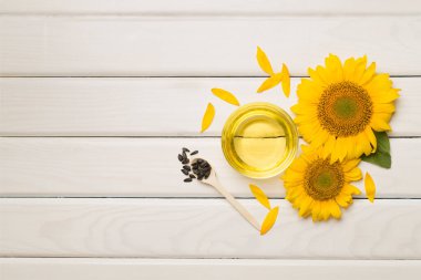 Sunflower oil, seeds and flower on wooden background.