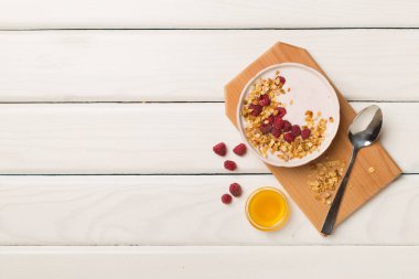 Bowl with granola, yogurt and fresh berries on wooden background, top view.