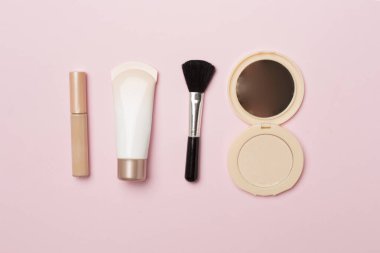Makeup products for skin tone on color background, top view.