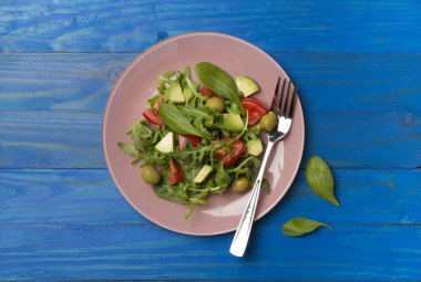 Tahta arka planda roka, ıspanak ve sebzeli taze salata..