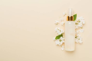 Renkli arka planda kozmetik şişesi ve çiçekli kompozisyon, üst görünüm