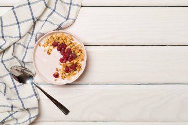 Bowl with granola, yogurt and fresh berries on wooden background, top view.