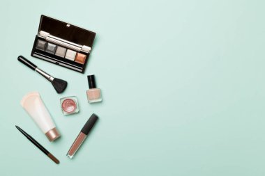 Different makeup products on color background, top view.