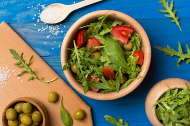 Tahta arka planda roka, ıspanak ve sebzeli taze salata..