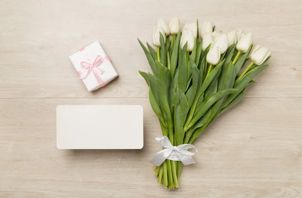 木製の背景に白いチューリップの花束とギフトボックス トップビュー — ストック写真