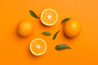 Flat lay with fresh oranges and leaves on color background.