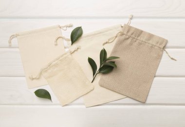 Small eco sacks with green leaves wooden on background. Top view