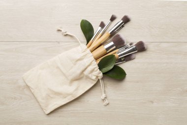 Natural biodegradable makeup brushes on wooden background, top view