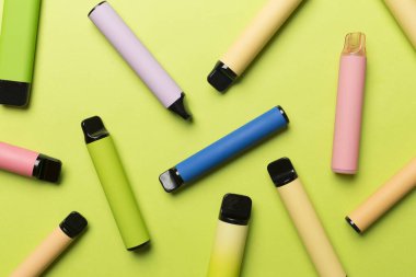 Disposable electronic cigarettes on color background, top view