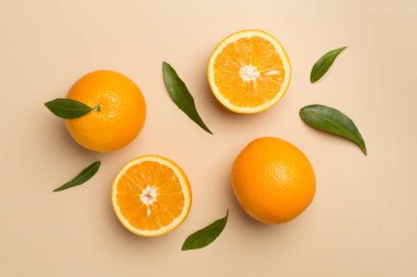 Flat lay with fresh oranges and leaves on color background.