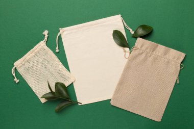 Small eco sacks with green leaves color on background. Top view.