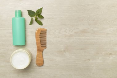 Ahşap arka planda ısırgan otu özlü şampuan ve saç maskesi..