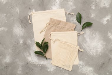 Small eco sacks with green leaves wooden on background. Top view.