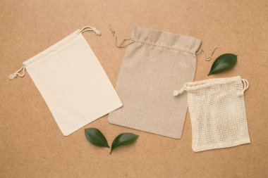 Small eco sacks with green leaves wooden on background. Top view.