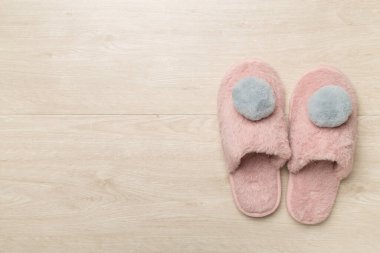 Soft pink slippers on wooden background, top view