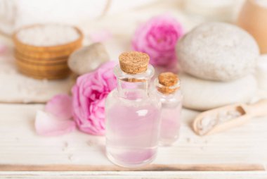 Ahşap masanın üzerinde pembe güller olan spa kompozisyonu