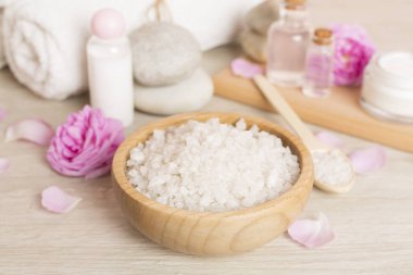 Ahşap masanın üzerinde pembe güller olan spa kompozisyonu